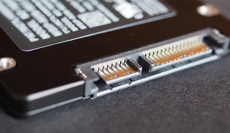 Disque dur SSD en gros plan montrant des puces de mémoire flash et des connecteurs SATA, soulignant la technologie de stockage rapide et compacte.