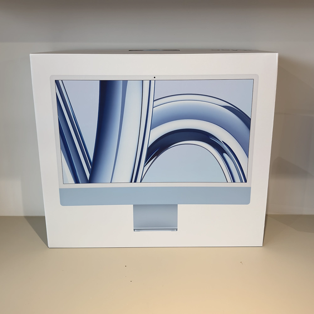Nouvel iMac M3 à côté de son emballage d'origine, positionné sur un bureau en bois clair, prêt pour l'installation et l'utilisation