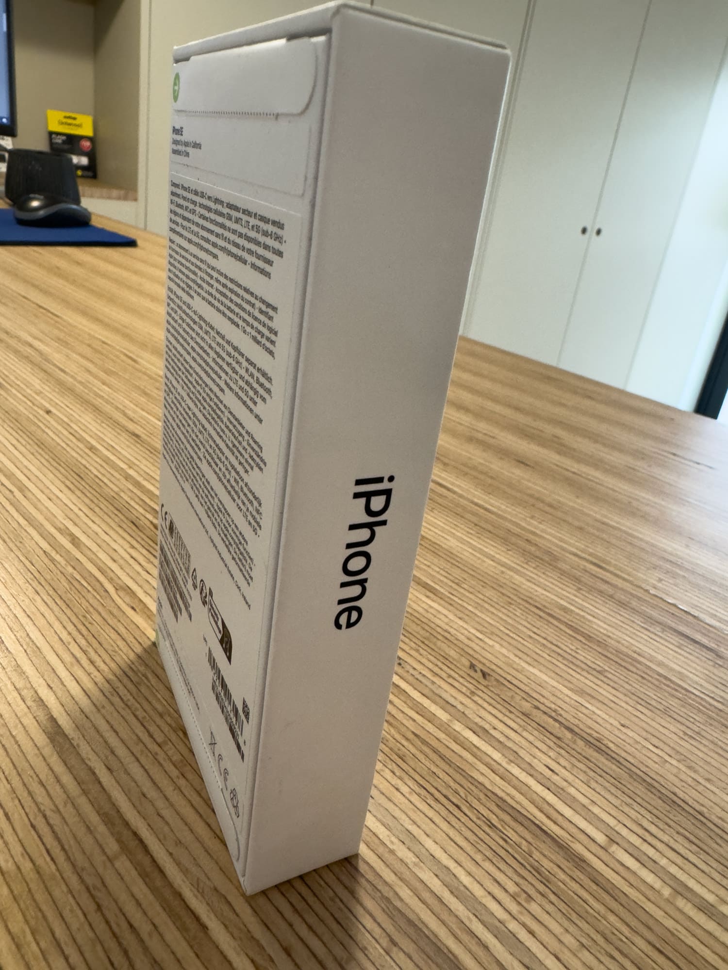 Boîte d'iPhone neuf sur table en bois.